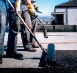 Handwerker verlegen Dachbahnen auf einem Flachdach